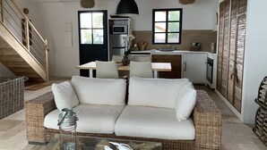 Un salon moderne avec un canapé, une table basse en verre et une cuisine en arrière-plan.