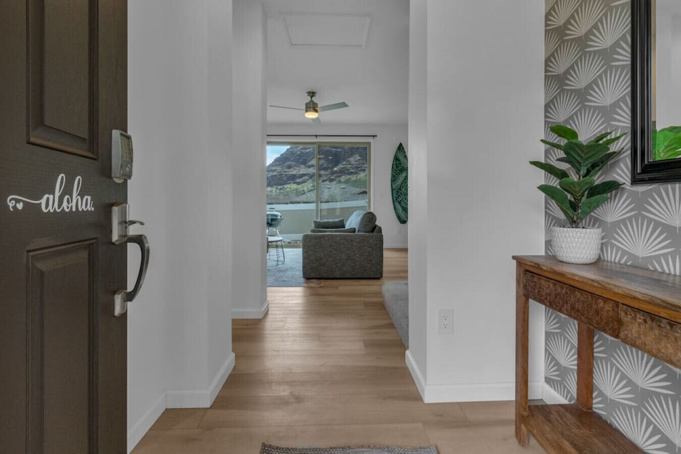 A hallway with a wooden floor, a dark brown door with a handle, and a wall with a geometric pattern.