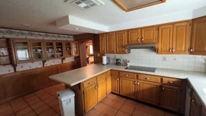 Una cocina con armarios de madera, encimera blanca y salpicadero de azulejos.