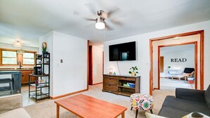 Een moderne woonkamer met een houten salontafel, een zwarte bank en een aan de muur bevestigde televisie.