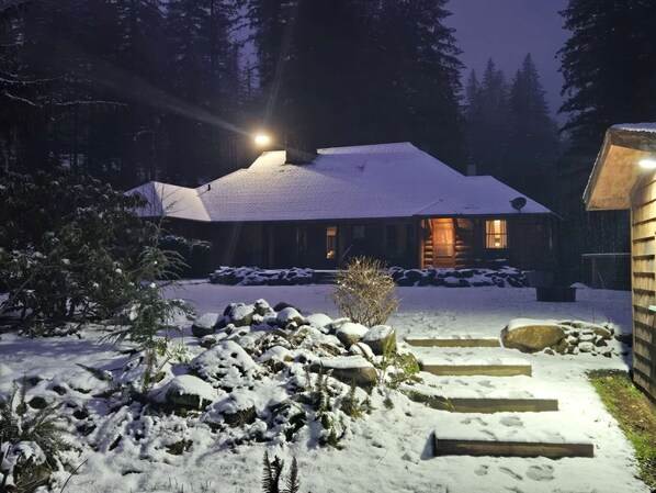 Escape to a serene winter wonderland in this charming cabin, surrounded by snow-covered landscape and a welcoming entrance.