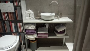 Ein Badezimmer mit Toilette, Waschbecken und Regalen mit Handtüchern.