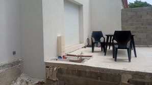 Eine Dachterrasse mit einer weißen Wand, einer geschlossenen Garagentür und zwei schwarzen Plastikstühlen.