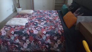Ein Schlafzimmer mit Bett, Schreibtisch, Stuhl, Zimmerpflanze und Kleiderschrank.
