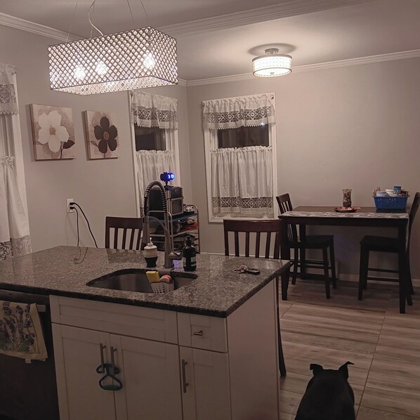 A kitchen with a granite countertop, a sink, and a dining area with a table and chairs.