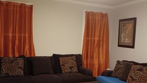 A living room with a dark brown sofa, a blue sofa, and a matching ottoman.