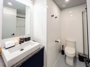 Une salle de bain moderne avec un lavabo blanc, un miroir et des toilettes.