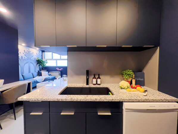 A modern kitchen with dark cabinets, a speckled countertop, and a built-in dishwasher.