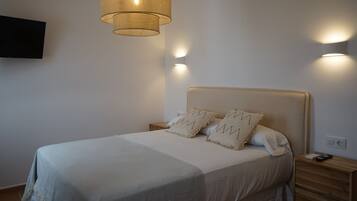 A neatly made bed with a headboard, two bedside tables, and a wall-mounted TV.