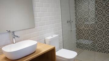Un baño con lavamanos, inodoro y ducha blancos.