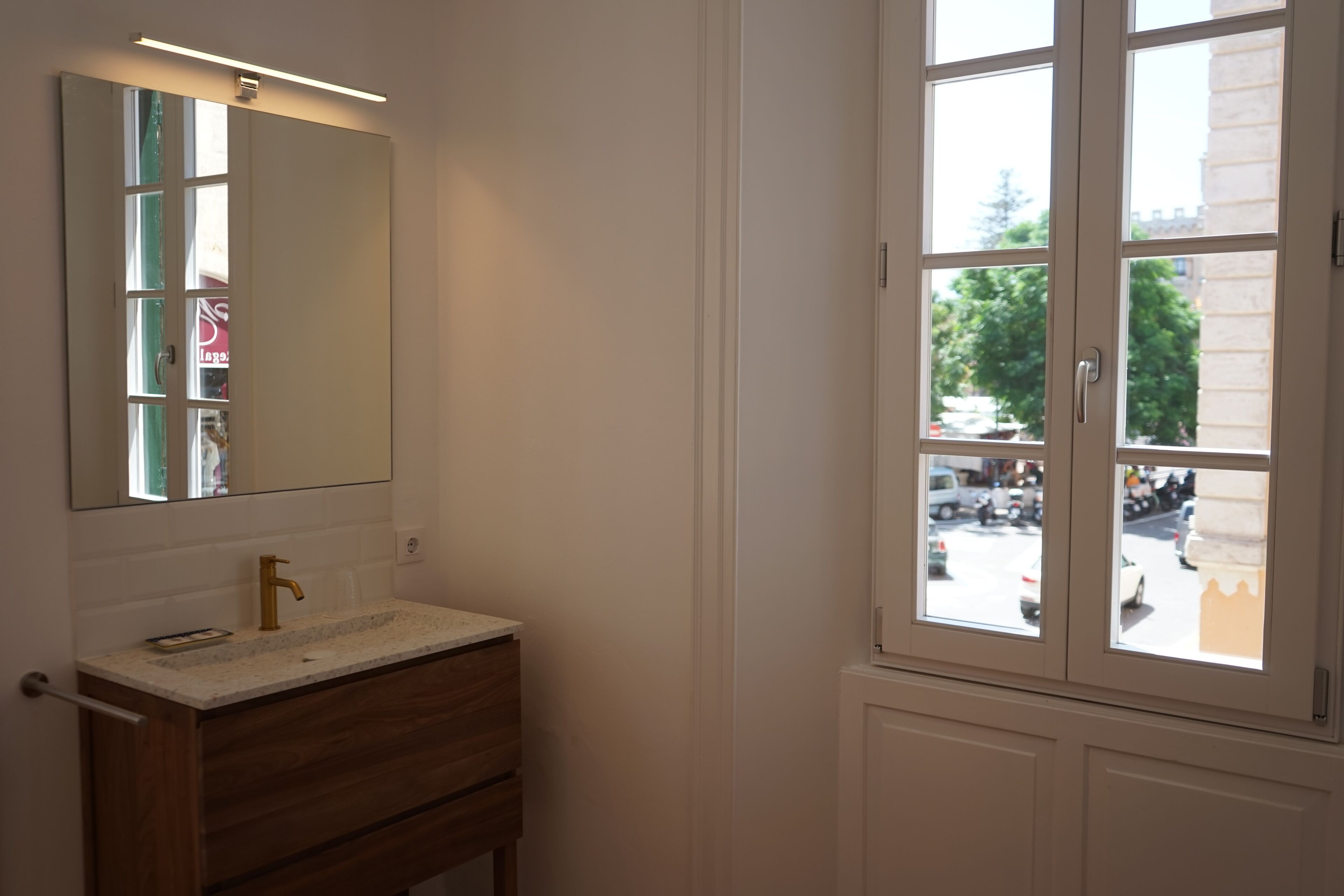 A bathroom with a white vanity, a gold faucet, and a large mirror.