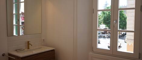 A bathroom with a white vanity, a gold faucet, and a large mirror.