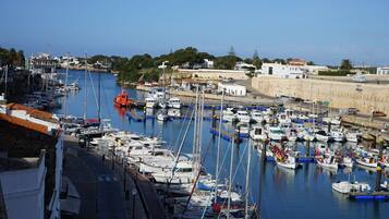 A marina with numerous boats docked, a clear sky, and buildings in the background.