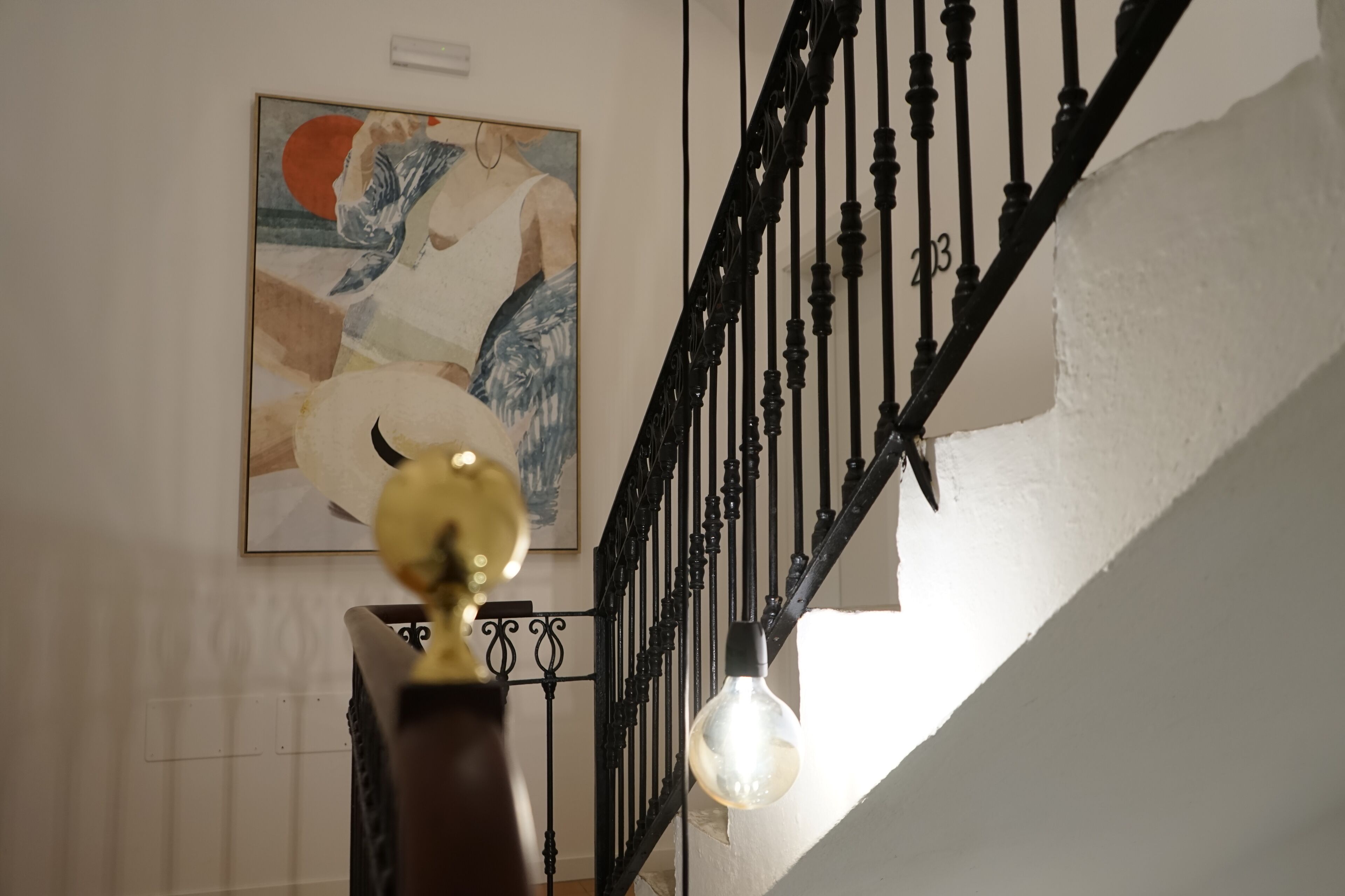 Un escalier avec une rampe noire et un luminaire.