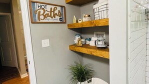 A bathroom with a shower, a sink, and a toilet. There are wooden shelves with toiletries and a sign that says "WASH BRUSH FLOSS." - Cozy Mid Century Modern Home Near Downtown (East Point)