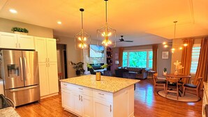 A modern kitchen with a central island, stainless steel appliances, and pendant lighting. - Cozy Mid Century Modern Home Near Downtown (East Point)