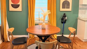 A dining area with a round wooden table, four wooden chairs, a vase with dried flowers, and a ceiling light fixture. - Cozy Mid Century Modern Home Near Downtown (East Point)
