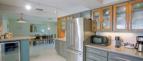 A modern kitchen with stainless steel appliances, wooden cabinets, and a dining area with a table and chairs.