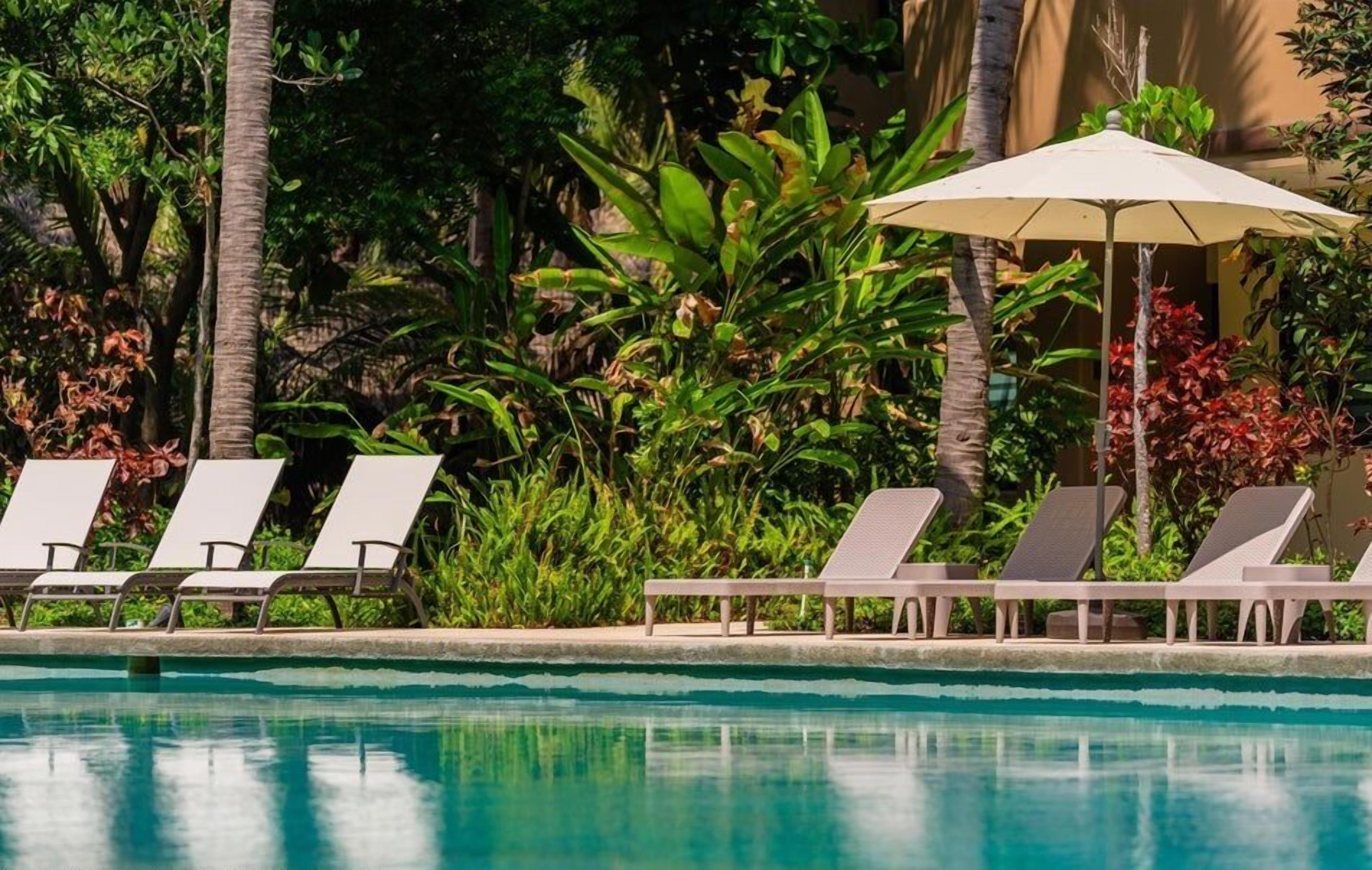 A poolside area with lounge chairs and an umbrella.
