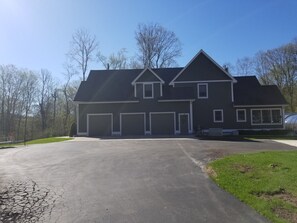 Stunning two-story home with a central entrance and garage doors, set amidst a well-manicured lawn and trees.