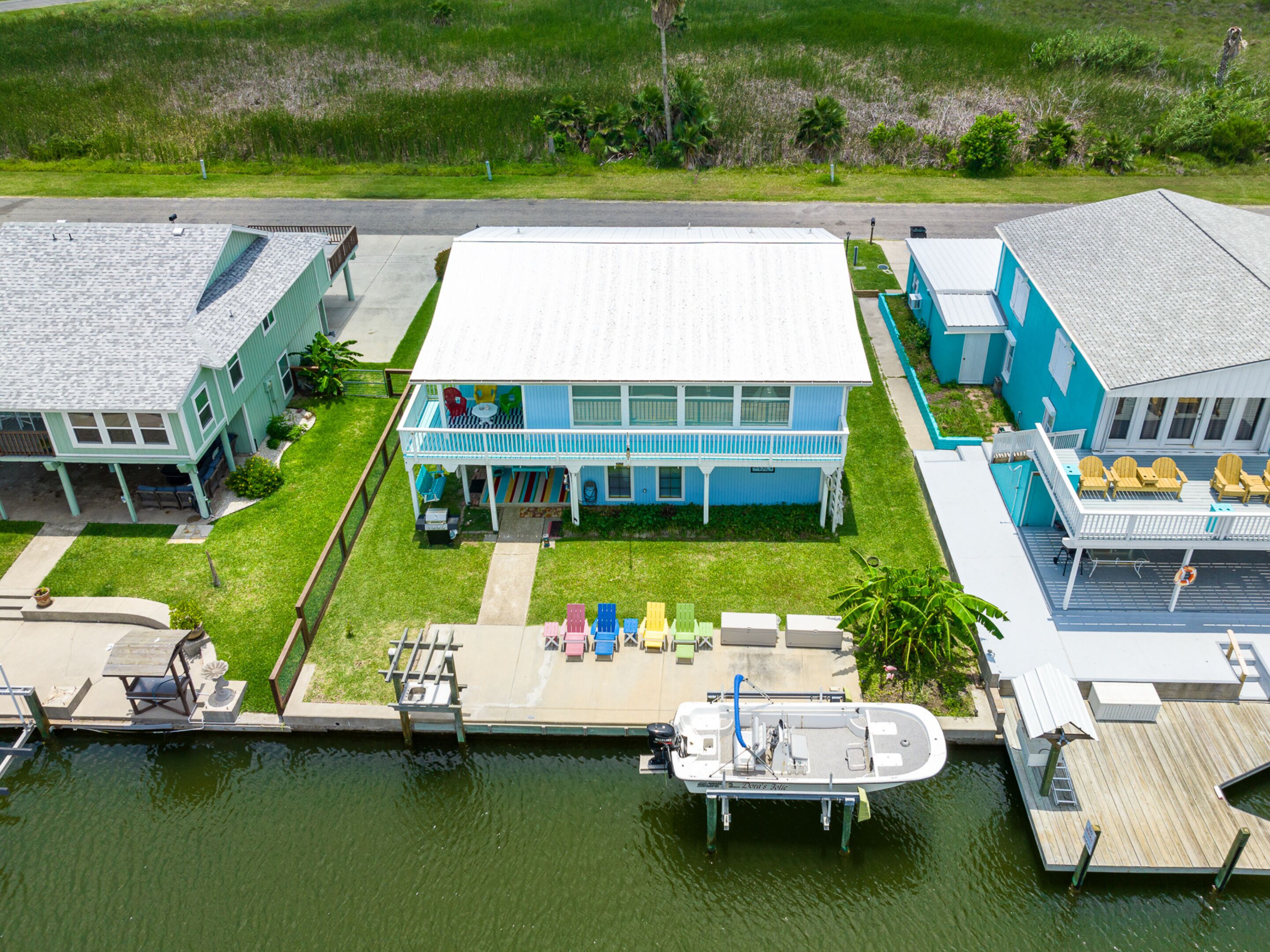 A waterfront property with a dock, a boat, and a house with a balcony.