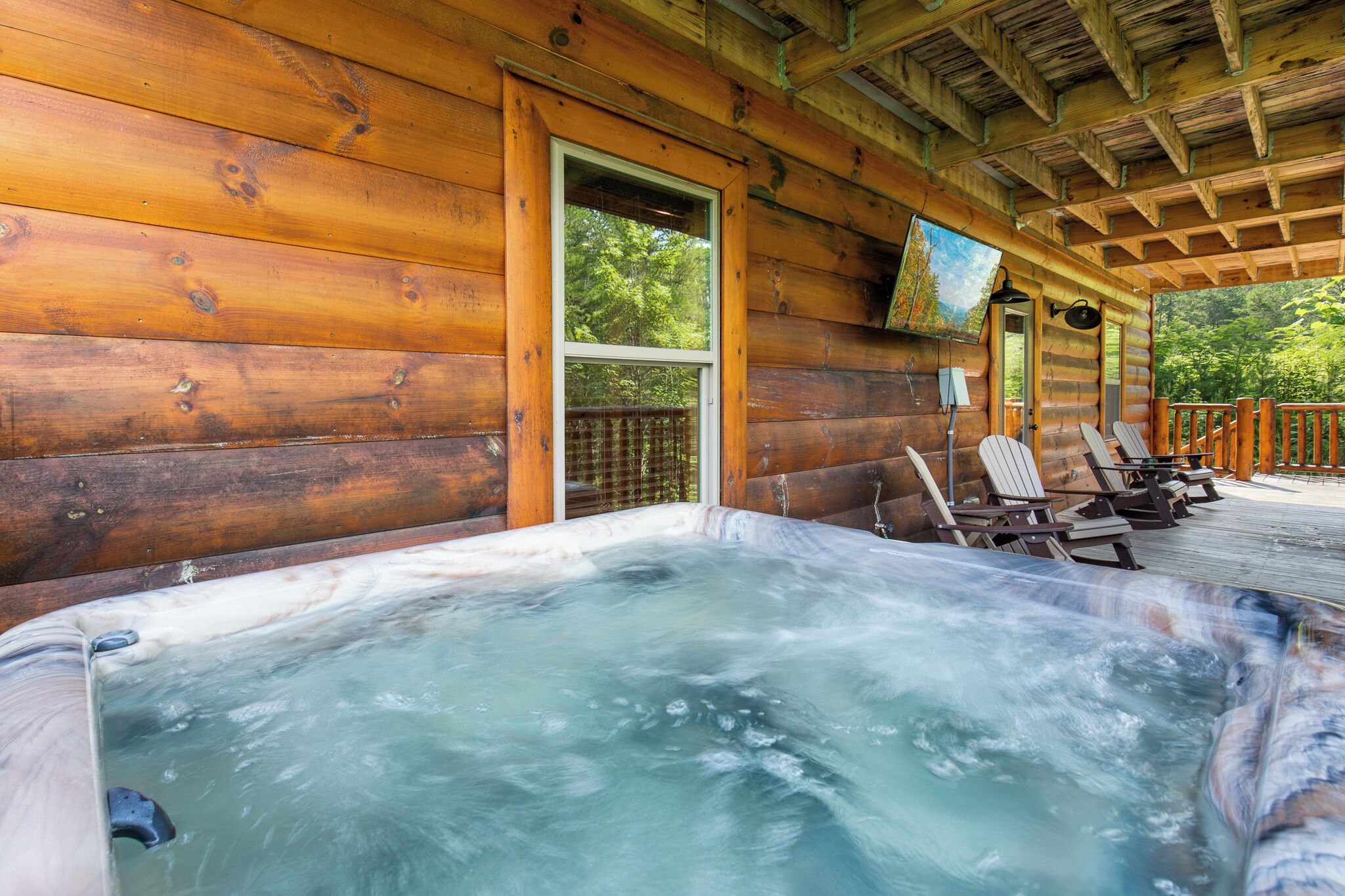 A wooden cabin with a hot tub and outdoor seating.