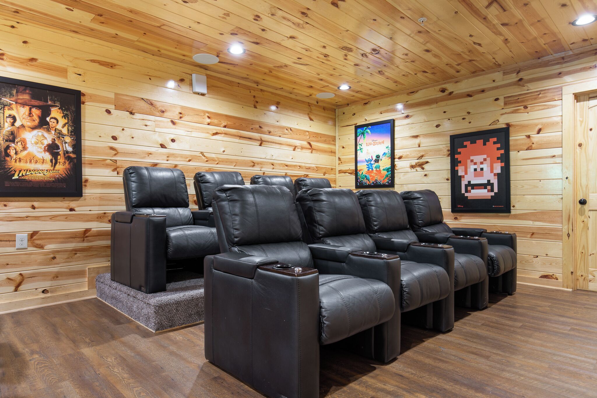 A wooden-paneled room with black leather recliners arranged in a row.