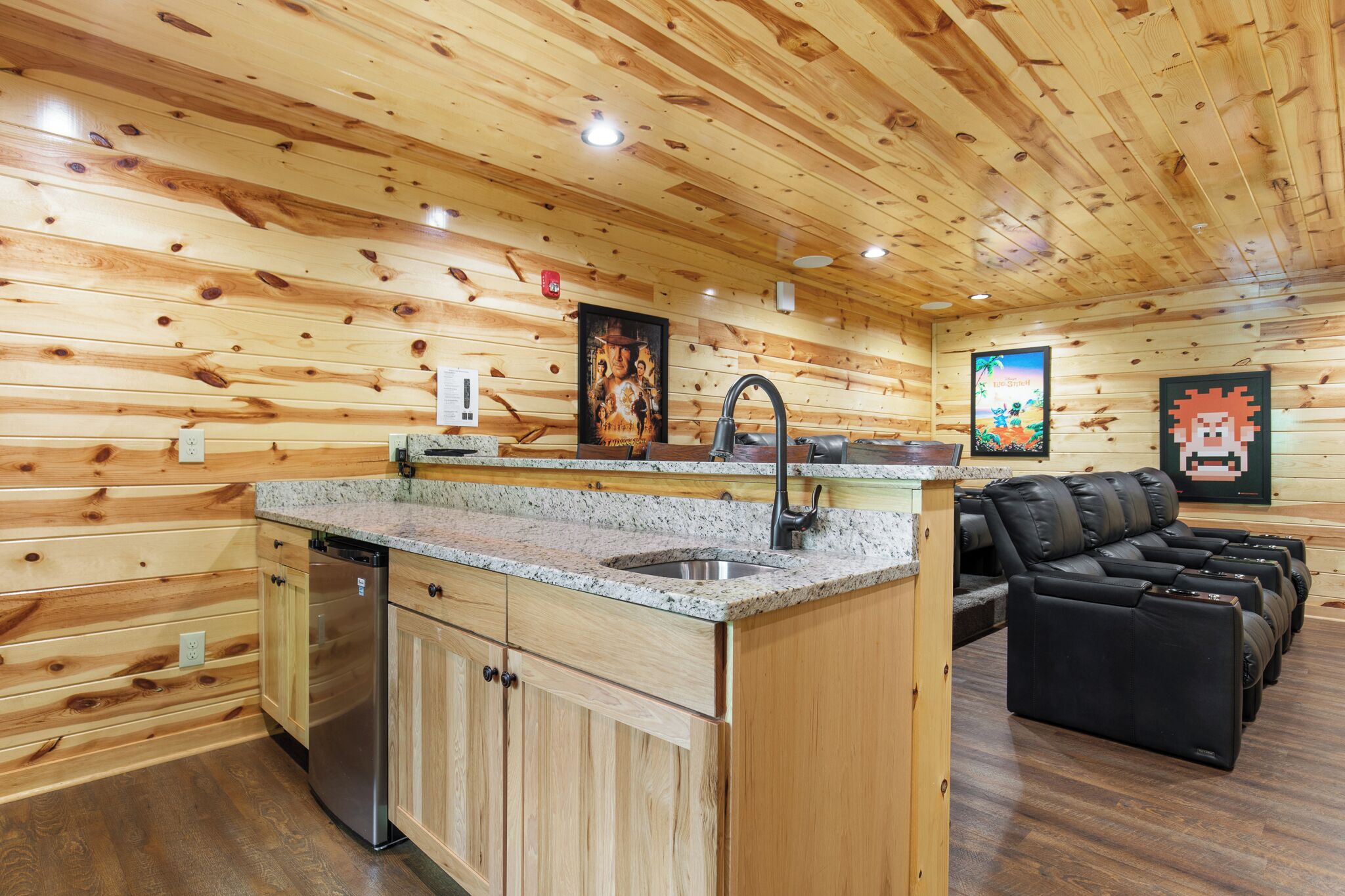 A wooden interior with a kitchen area, a sink, and a seating area with leather sofas.