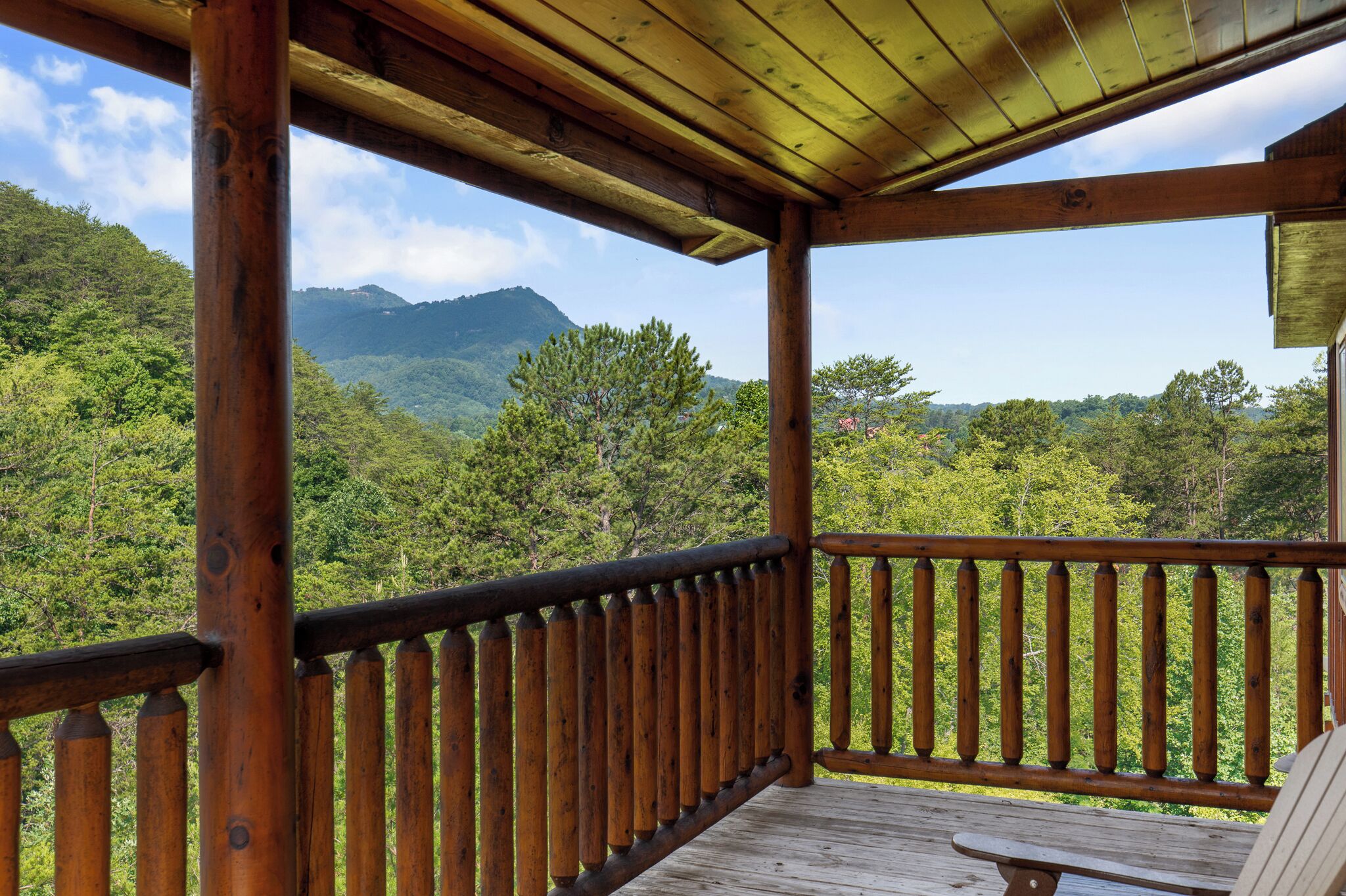 Une terrasse en bois offrant une vue sur une chaîne de montagnes boisées.