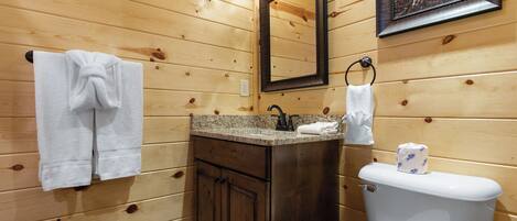 A wooden cabin bathroom with a sink, mirror, and toilet.