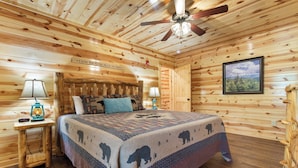 A log cabin bedroom with a bed, two nightstands, a ceiling fan, and a framed picture on the wall. - Mountain High Cinema by Jackson Mountain Rentals (Sevierville)