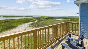 A wooden deck with a view of a coastal landscape, including a beach and marshy areas. - Bayfront Nirvana! by Ryson Vacation Rentals (Galveston)