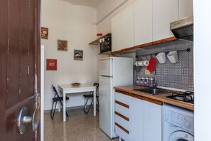 A compact kitchen with a refrigerator, microwave, stove, and washing machine.