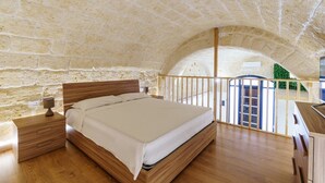 Ein Schlafzimmer mit einem hölzernen Bett, einem Nachttisch und einer Steinwand.