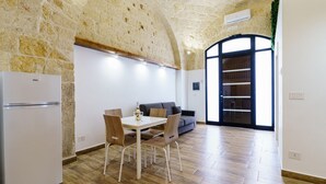 Eine Küche mit Steinwand, einem weißen Kühlschrank, einem Esstisch mit Stühlen und einem Sofa.