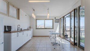 Eine moderne Küche mit einem großen Fenster, einem Essbereich mit transparenten Stühlen und Blick auf eine Stadtlandschaft.