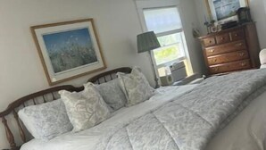 A bedroom with a large bed, a dresser, a nightstand, a lamp, and a framed picture on the wall. - House in Newport (Newport)