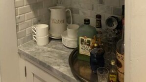 A kitchen with white cabinets, a marble countertop, and a tiled backsplash. - House in Newport (Newport)