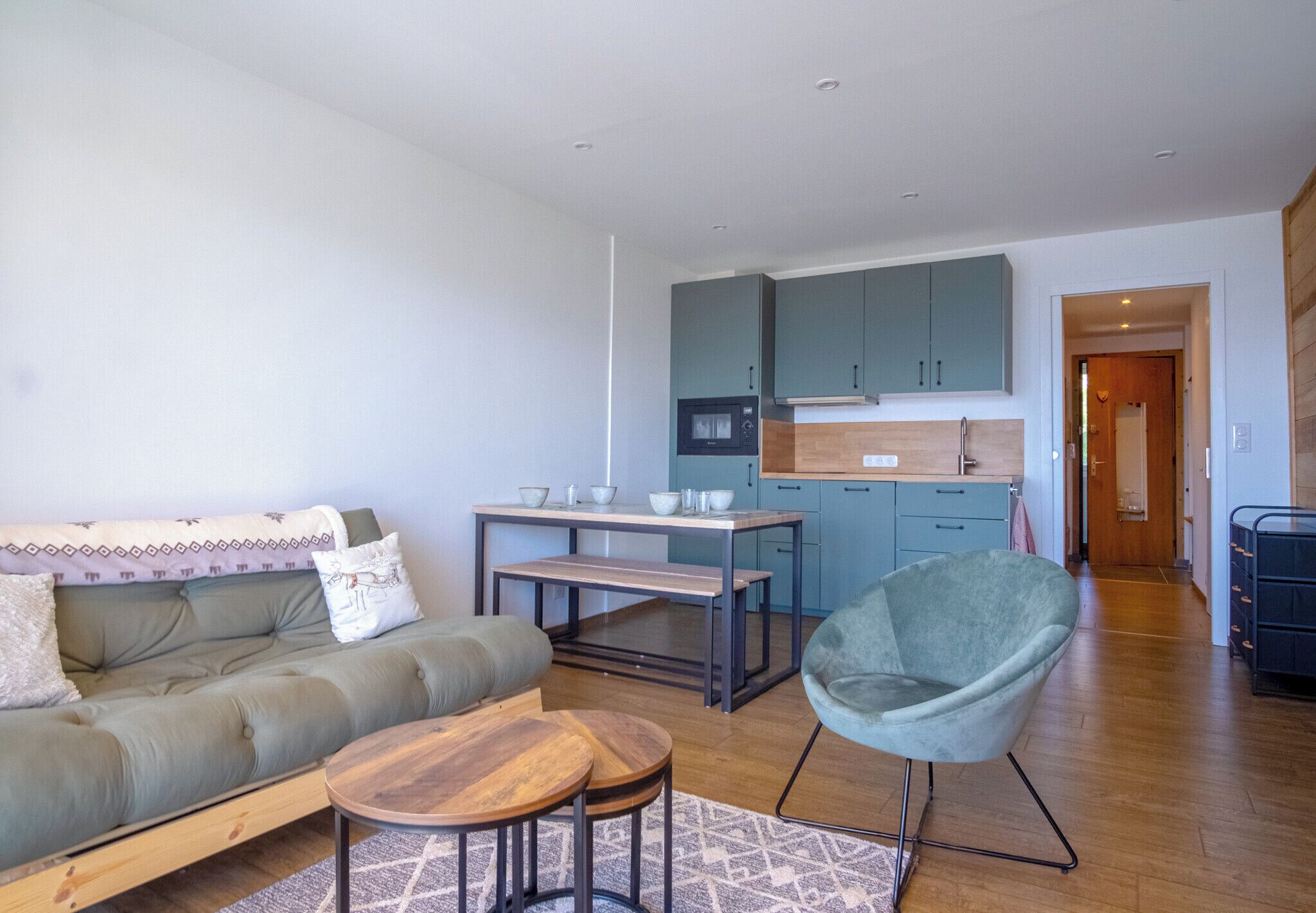 A modern living room with a sofa, coffee table, and a dining area with a table and chairs.