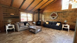 A cozy living room with wooden walls, a fireplace, two sofas, a coffee table, and a TV. - Royal Cabin between Lake Quachita and Hot Springs  (Royal)
