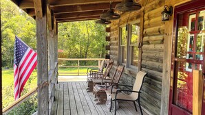 A wooden porch with a covered seating area, an American flag, and a 'Hog Country' sign. - Royal Cabin between Lake Quachita and Hot Springs  (Royal)