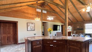 A spacious kitchen with a large island, wooden cabinets, and a vaulted ceiling. - Royal Cabin between Lake Quachita and Hot Springs  (Royal)