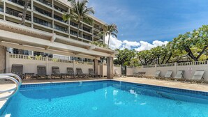 A hotel pool area with a clear blue pool, lounge chairs, and a multi-story building with balconies. - Kihei Akahi D-104 (Kihei)