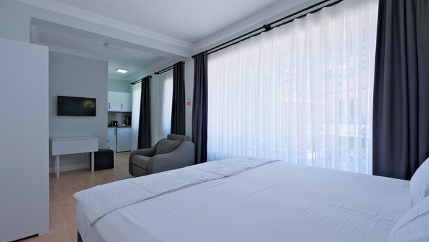 A hotel room with a bed, a desk, a chair, and a TV. - Central Flats Fethiye (Fethiye)