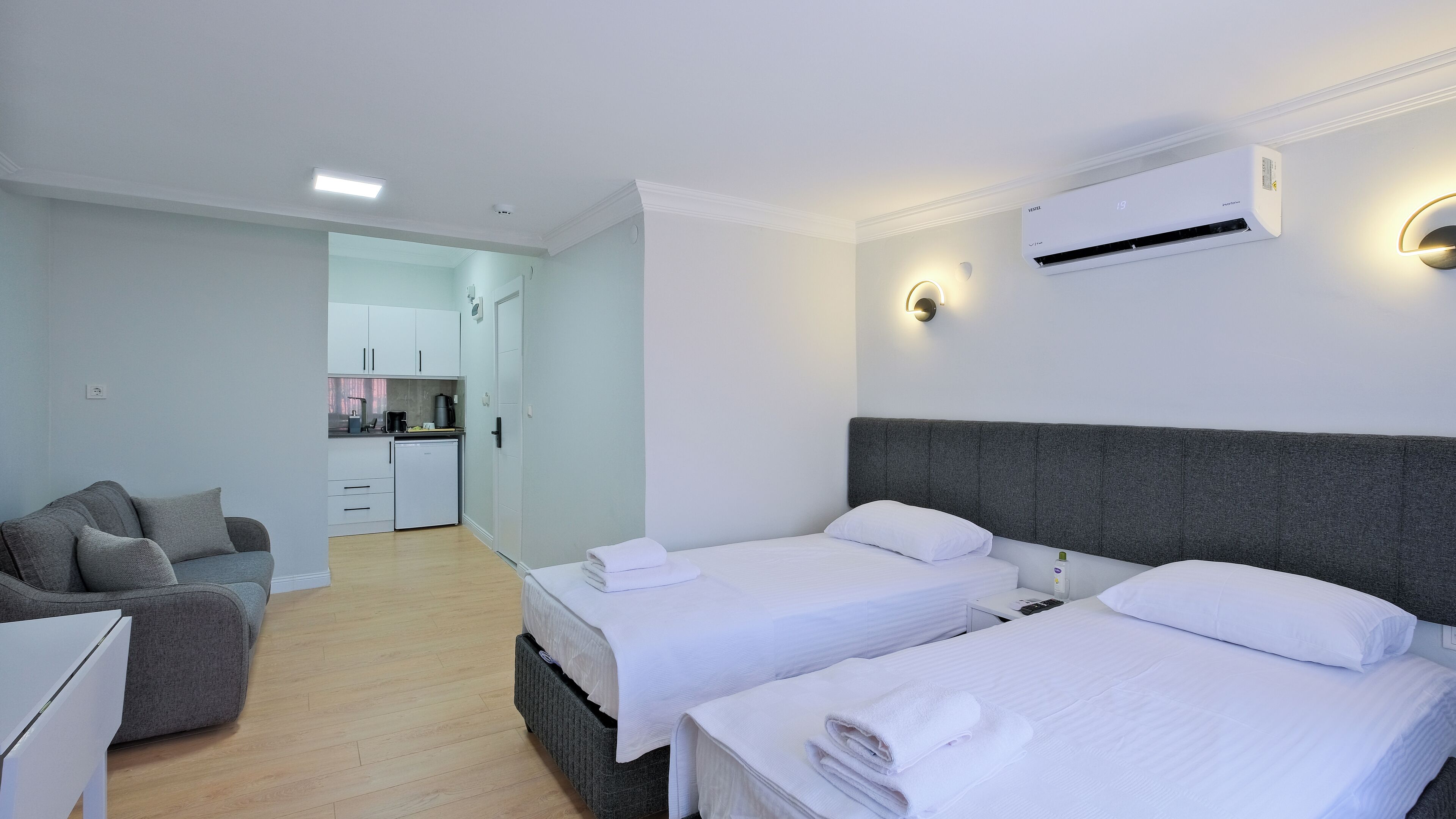 Una camera d'albergo con due letti, angolo cottura e salottino.