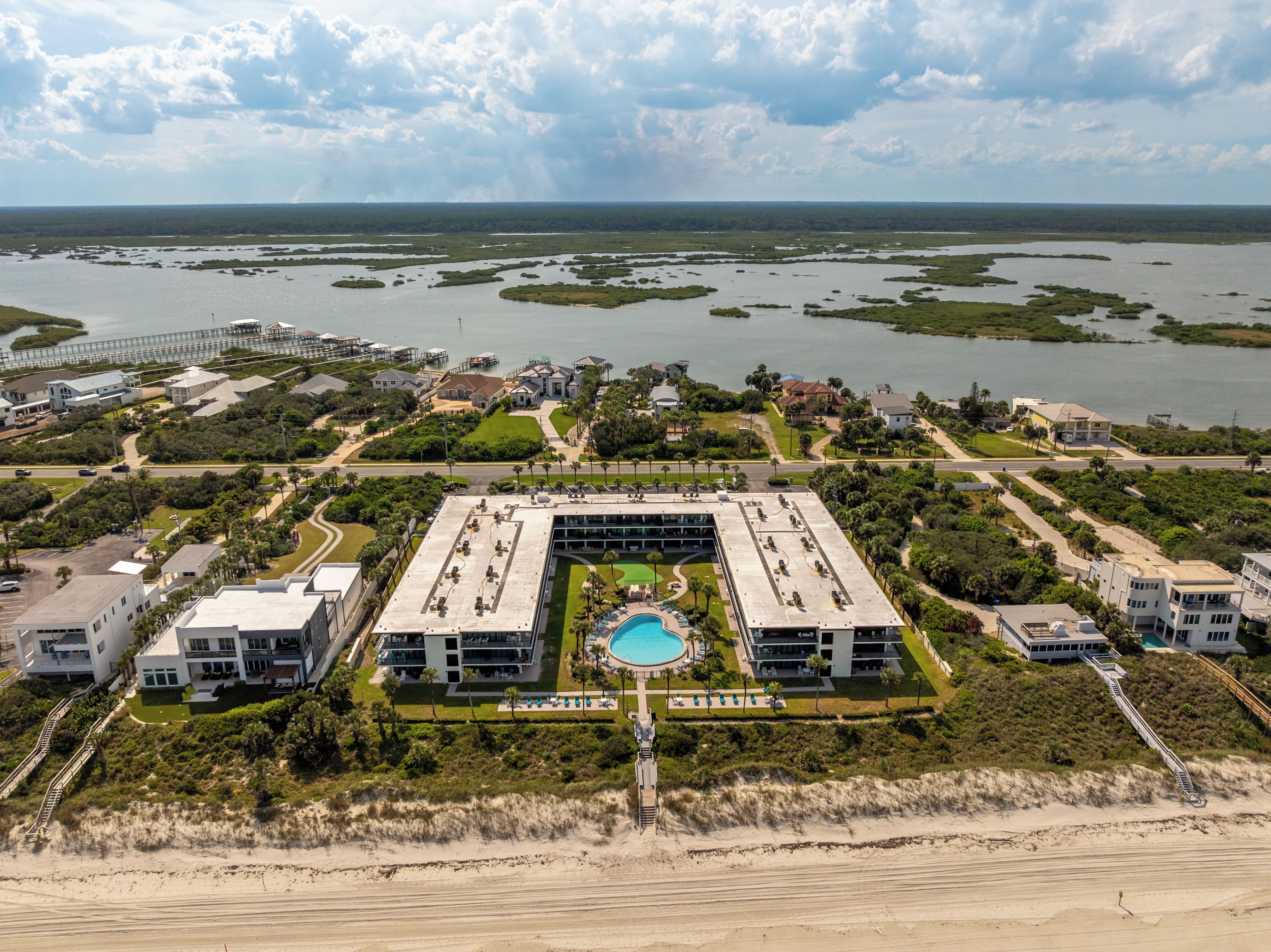 A resort with a central building, a swimming pool, and a beach.