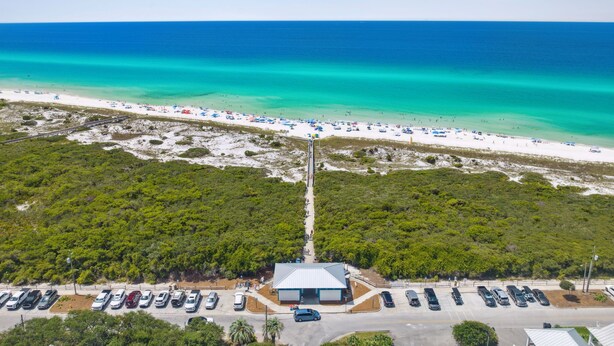 An aerial view of a beach with a parking lot, a building with a blue roof, and a clear view of the ocean. - 2-bedroom vacation home just a short walk to Rosemary Beach (Rosemary Beach)