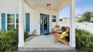 A covered porch with two wooden Adirondack chairs and a blue door. - 2-bedroom vacation home just a short walk to Rosemary Beach (Rosemary Beach)