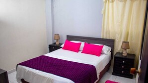 A bed with a white and purple bedspread, two pink pillows, and two nightstands with lamps. - Hotel Ruta Del Mar (Santa Marta)