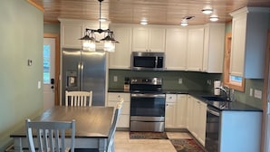 Una cocina moderna con armarios blancos, electrodomésticos de acero inoxidable y techo de madera.